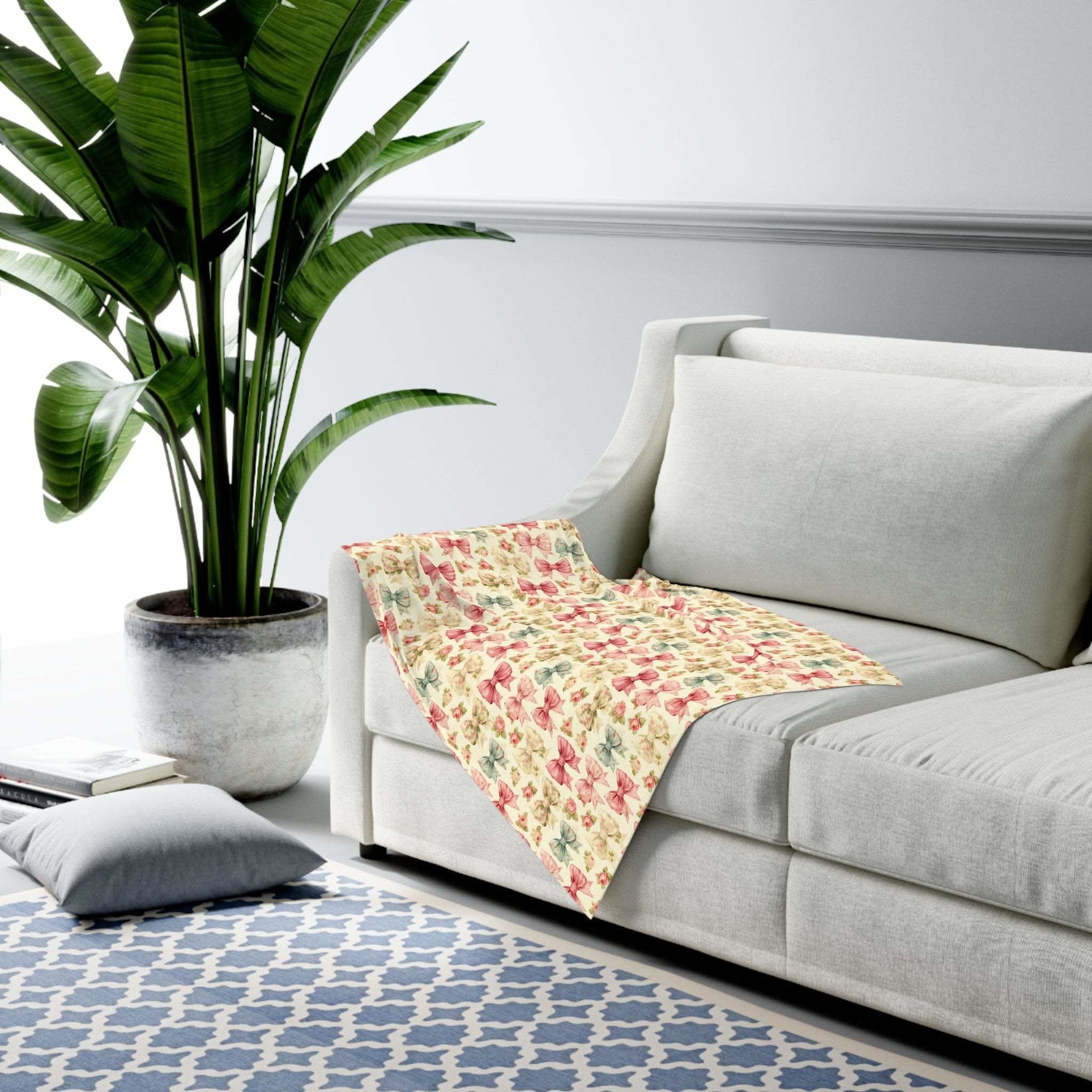 Floral Coquette Bows swaddle blanket draped on gray sofa in modern living room