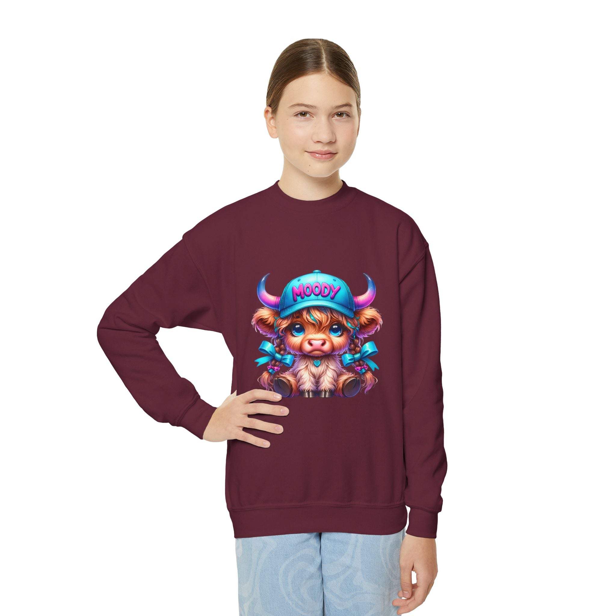 Youth wearing maroon Moody Girl Highland Cow sweatshirt with colorful cartoon cow design on chest