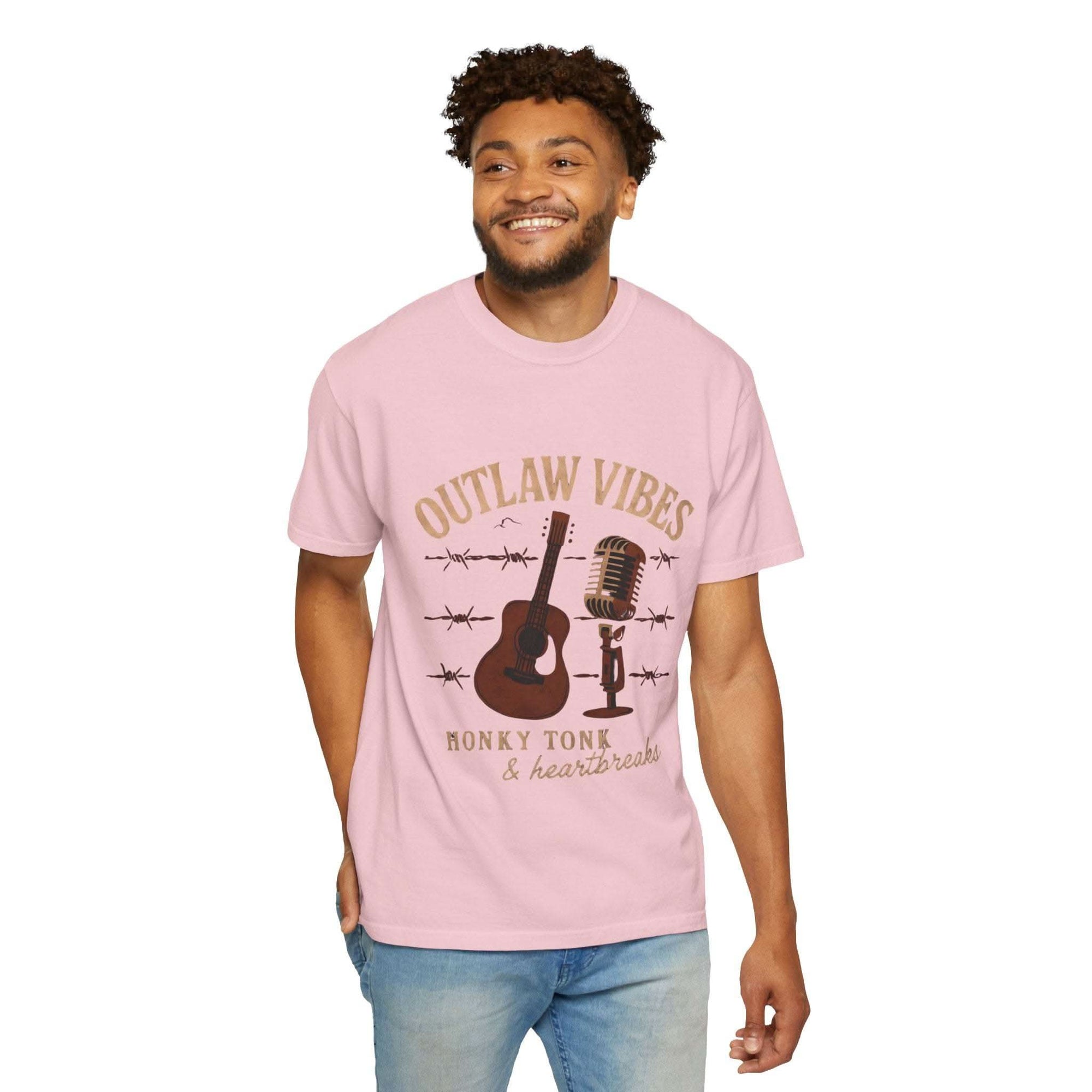 Man wearing a pink t-shirt with 'Outlaw Vibes' graphic design on a white background