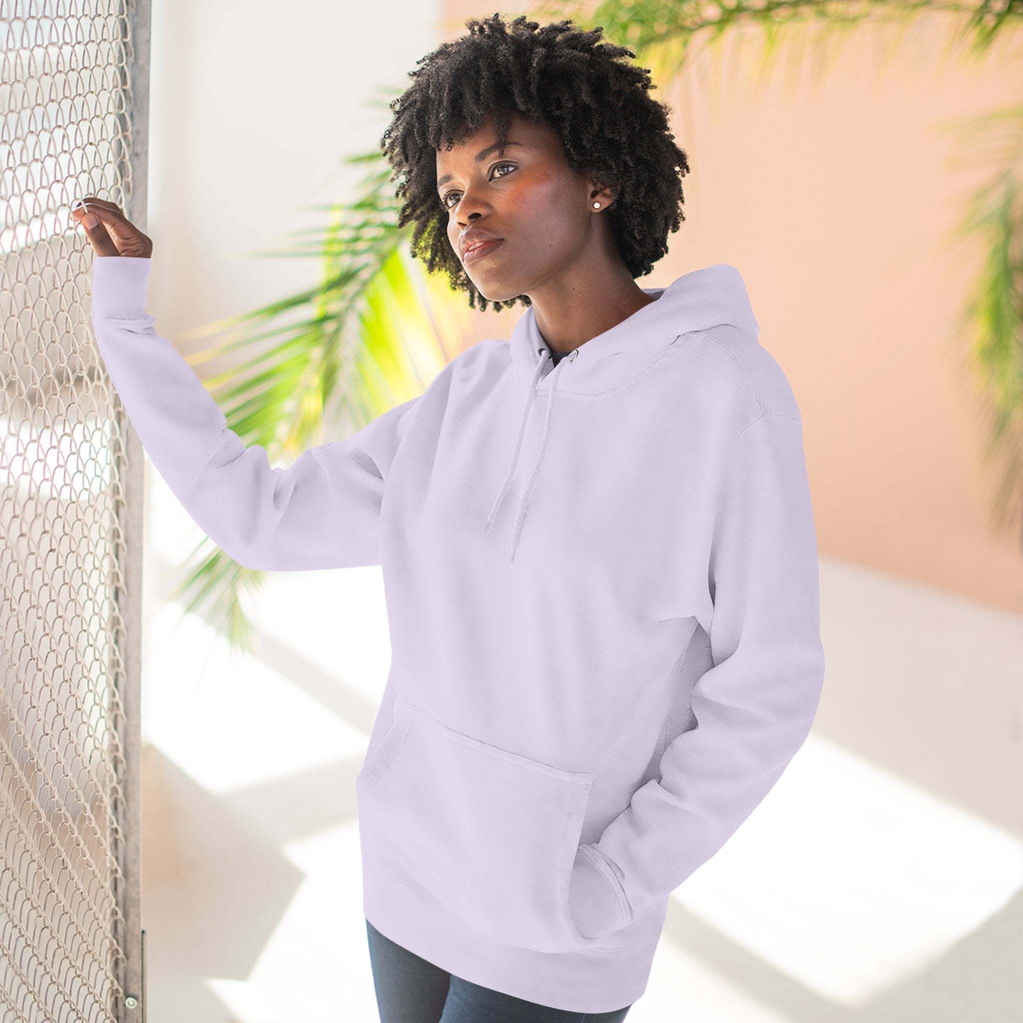 Woman wearing cozy light pink fleece hoodie with kangaroo pocket and adjustable drawstring hood indoors