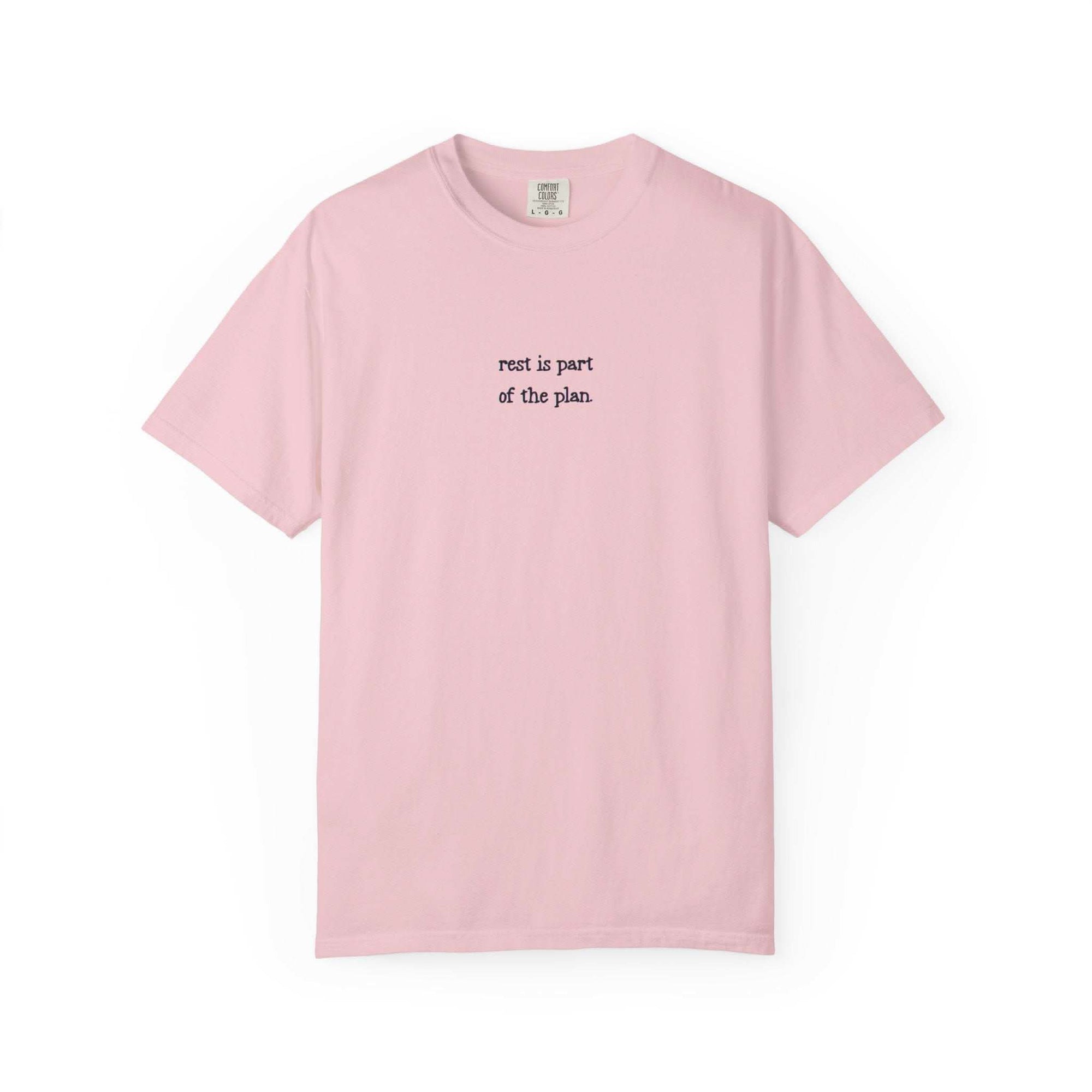 Pink t-shirt with text 'rest is part of the plan' on a white background