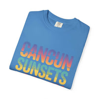 Folded blue t-shirt with 'Cancun Sunsets' text in rainbow colors on a white background