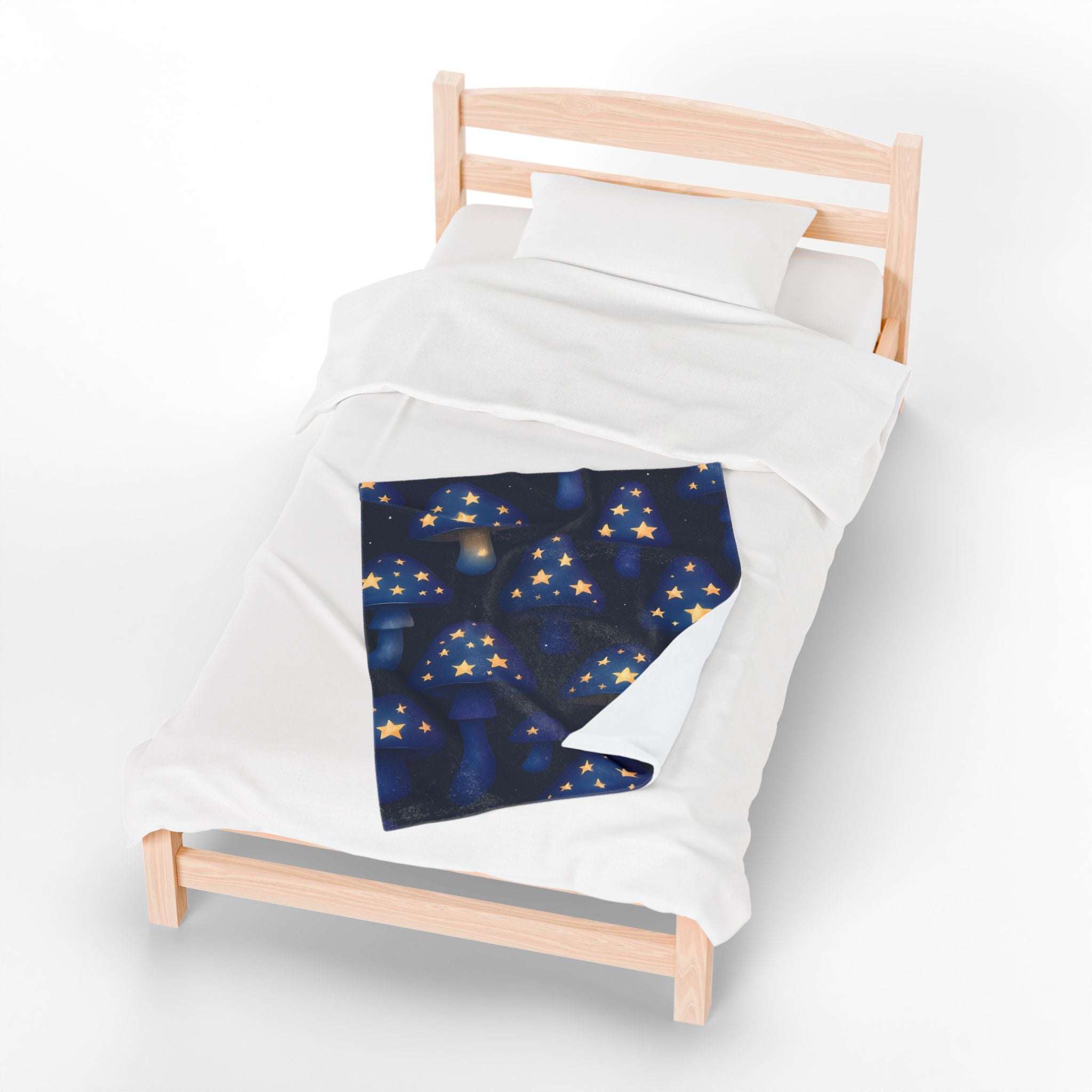 Plush blanket with whimsical glowing mushroom and star design on bed