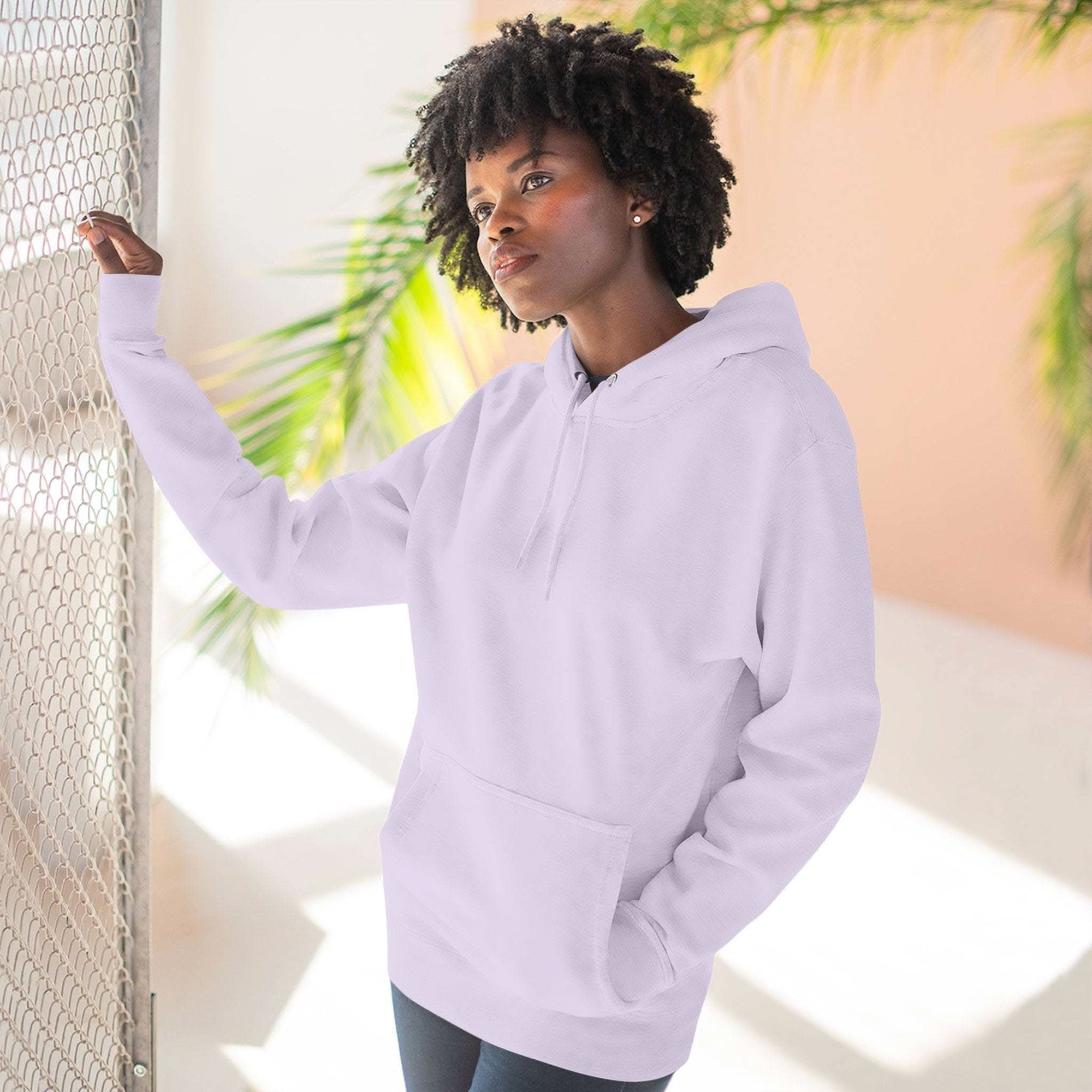 Woman wearing cozy pink fleece hoodie with kangaroo pocket standing indoors with sunlight and plants