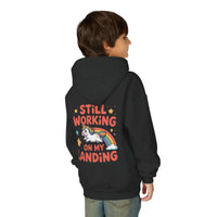 Kids hoodie with colorful unicorn rainbow design and playful "Still Working On My Landing" text