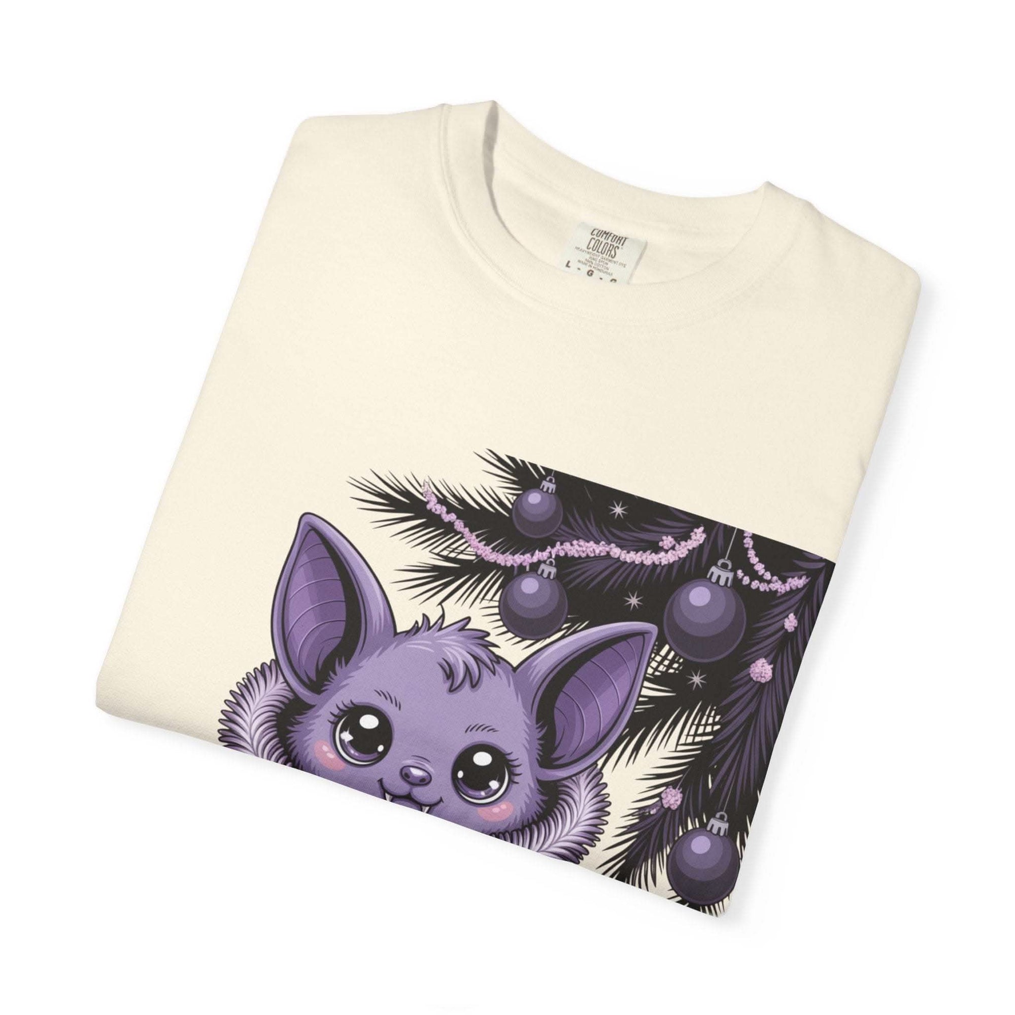 Folded light-colored Gothmas Bat T-Shirt featuring a purple bat and holiday decorations graphic.