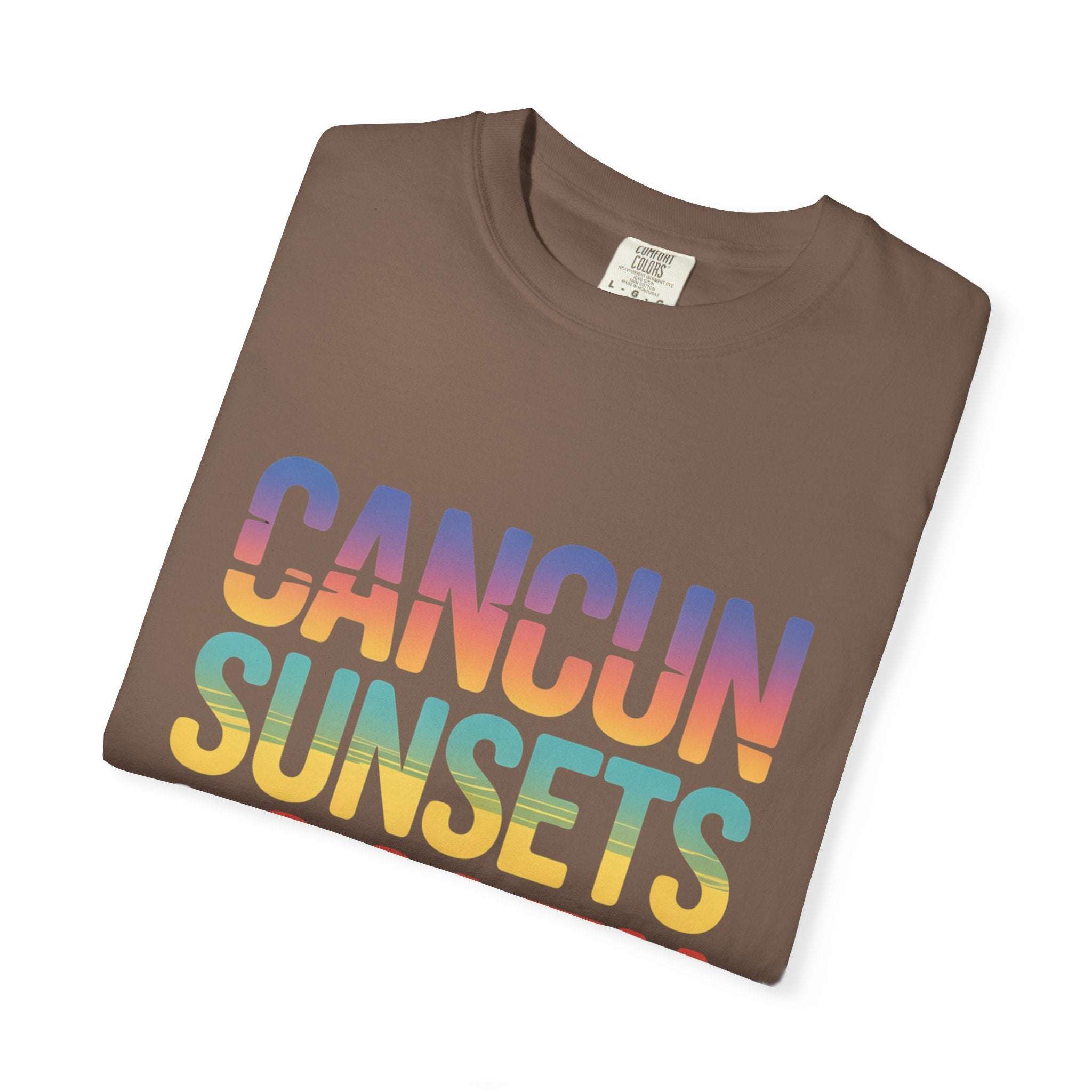 Folded brown t-shirt with 'Cancun Sunsets' text in rainbow colors on a white background