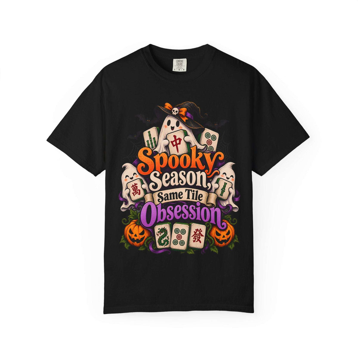 Flat lay of a black Halloween mahjong T-shirt with ghosts, pumpkins, mahjong tiles and “Spooky Season, Same Tile Obsession” lettering.