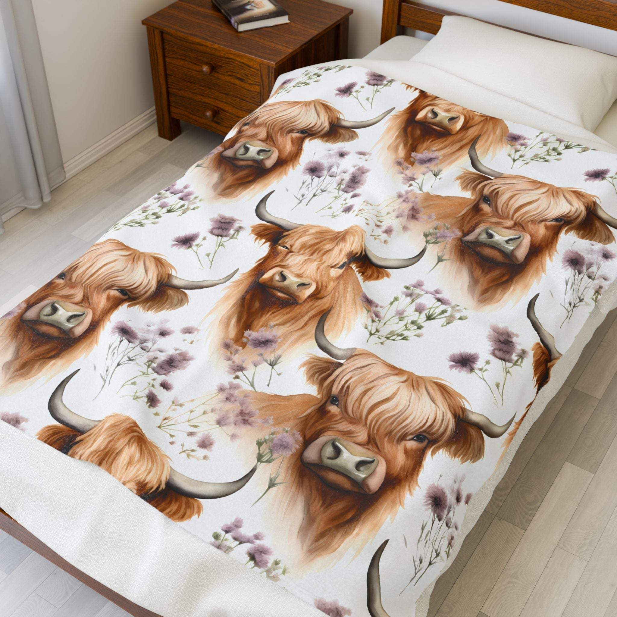 Plush blanket with floral highland cow design on bed in cozy bedroom setting