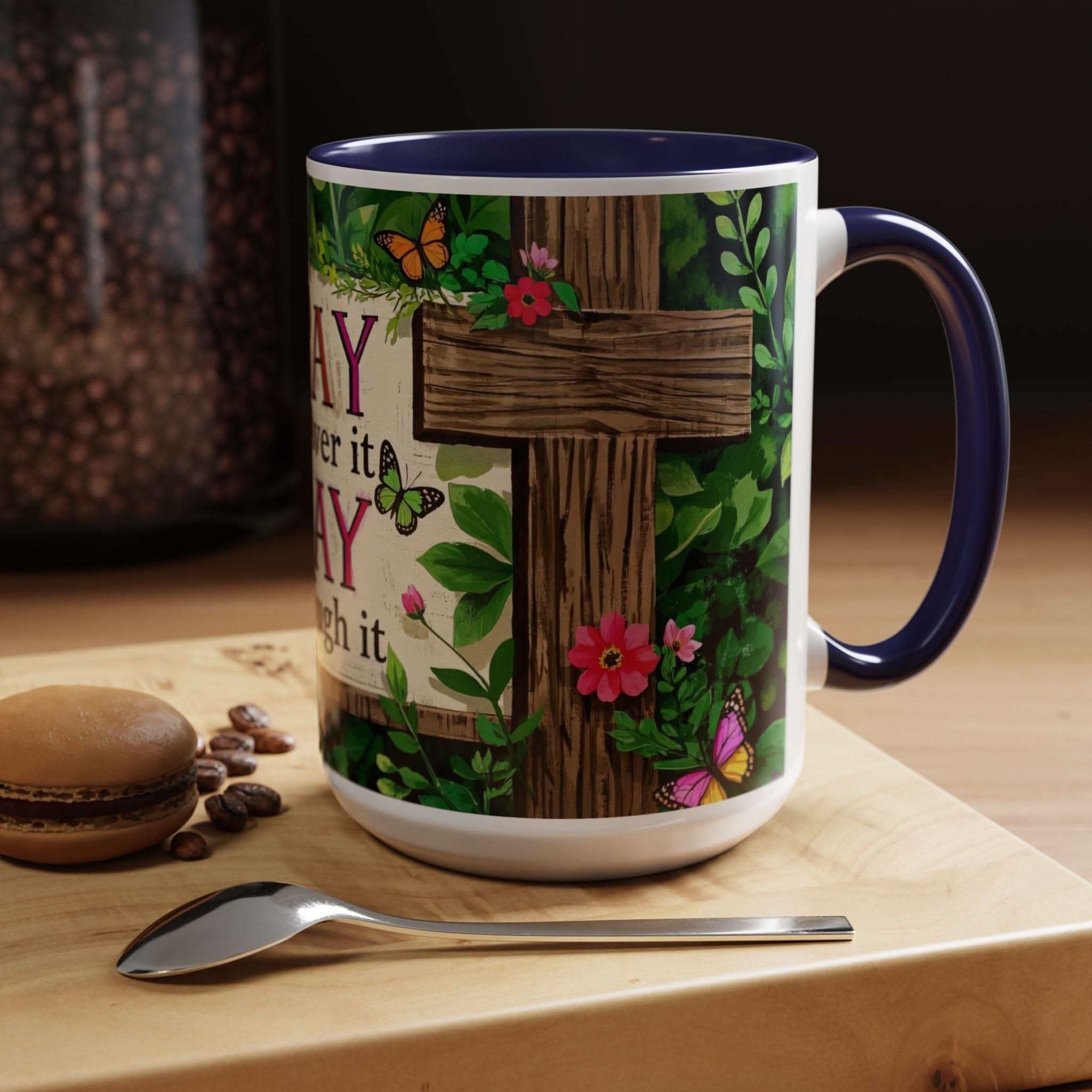 Mug with cross and floral design on a wooden surface with coffee beans and a macaron.