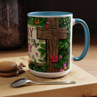 Mug with cross and floral design on a wooden surface with coffee beans and a cookie.