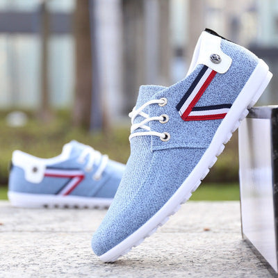 Men's soft-soled blue canvas casual shoes with white laces and red, white, and black striped detailing