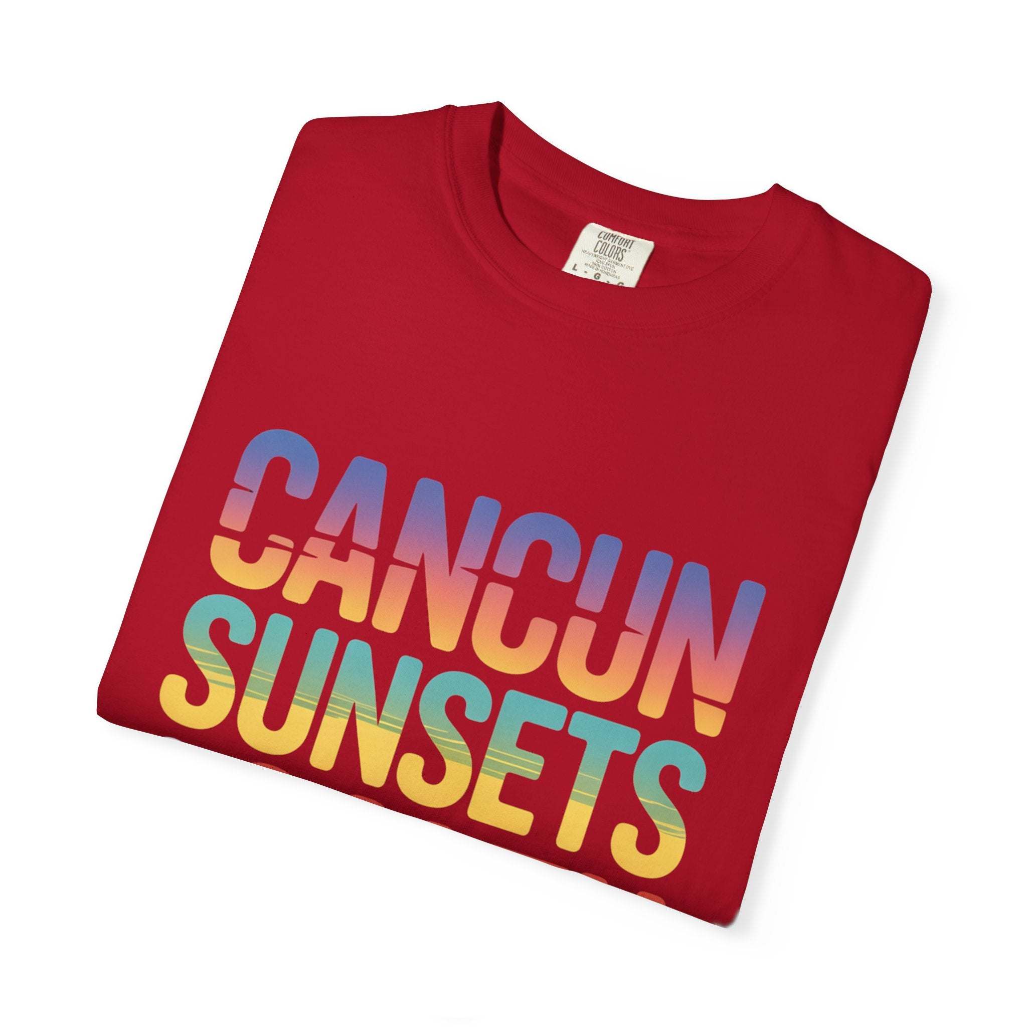 Folded red t-shirt with 'Cancun Sunsets' text in gradient colors on a white background