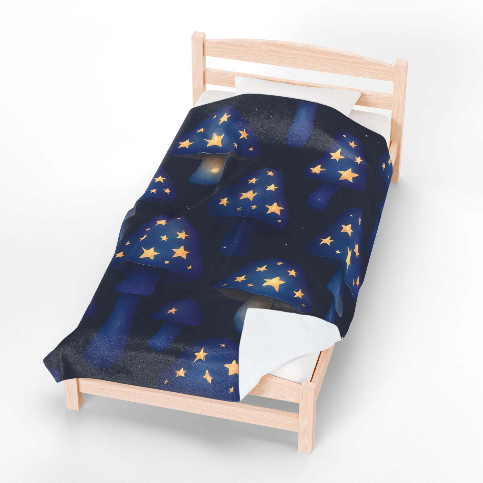 Velveteen plush blanket with whimsical glowing star mushrooms on dark background on bed