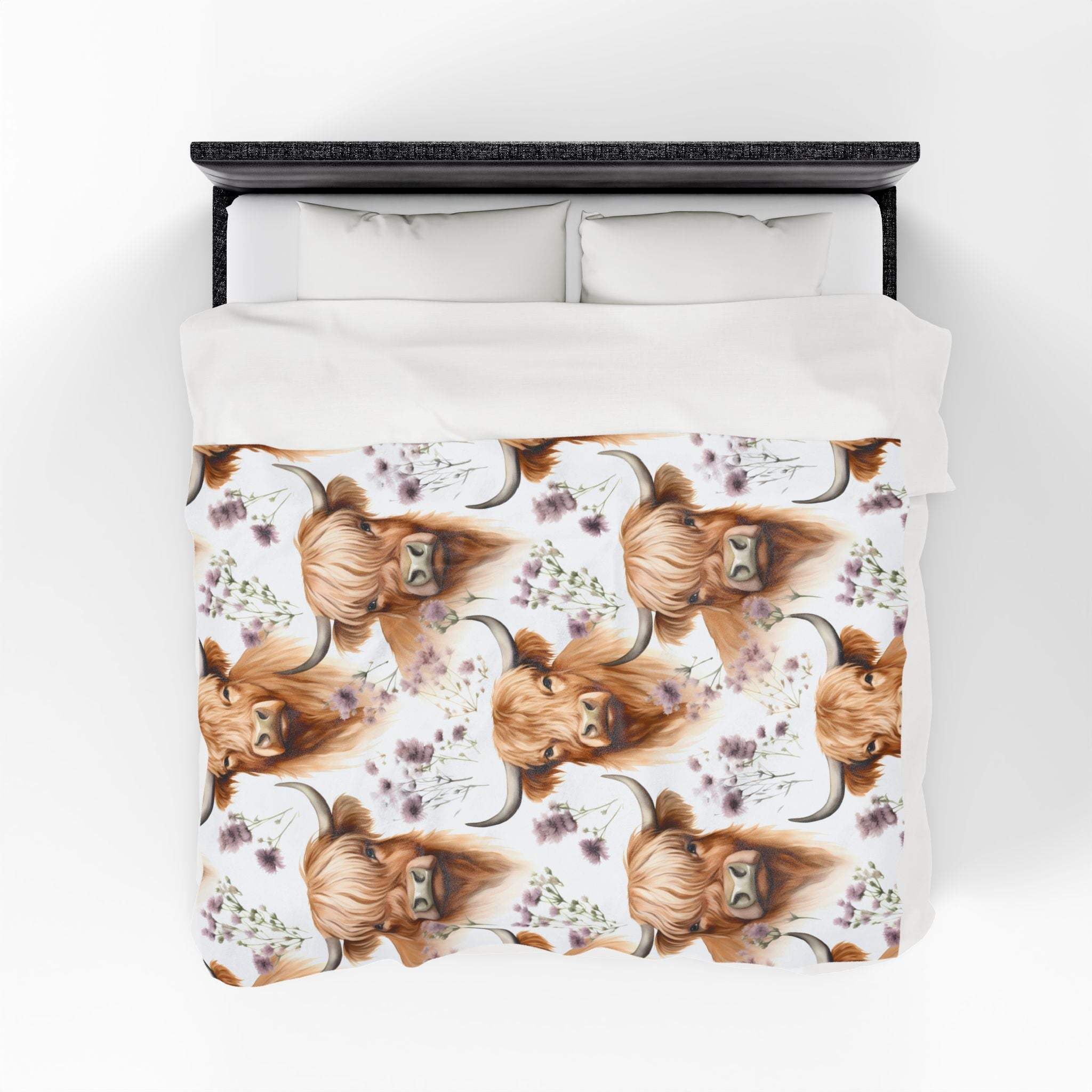 Plush blanket with floral highland cow design on a bed