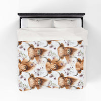 Plush blanket with floral highland cow design on a bed