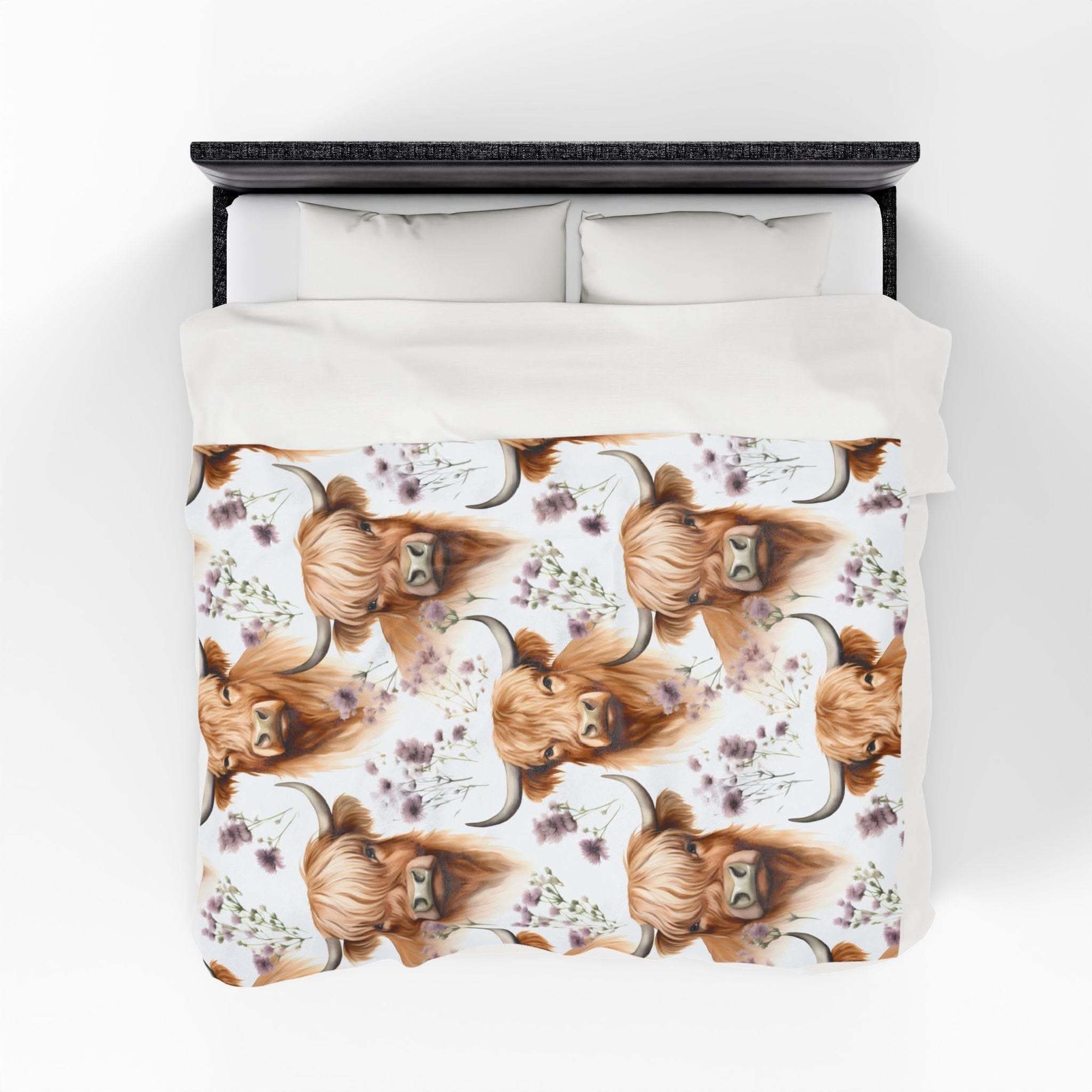Plush blanket with floral highland cow design on a bed