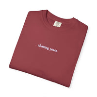 Folded maroon t-shirt with 'choosing peace' text on a white background