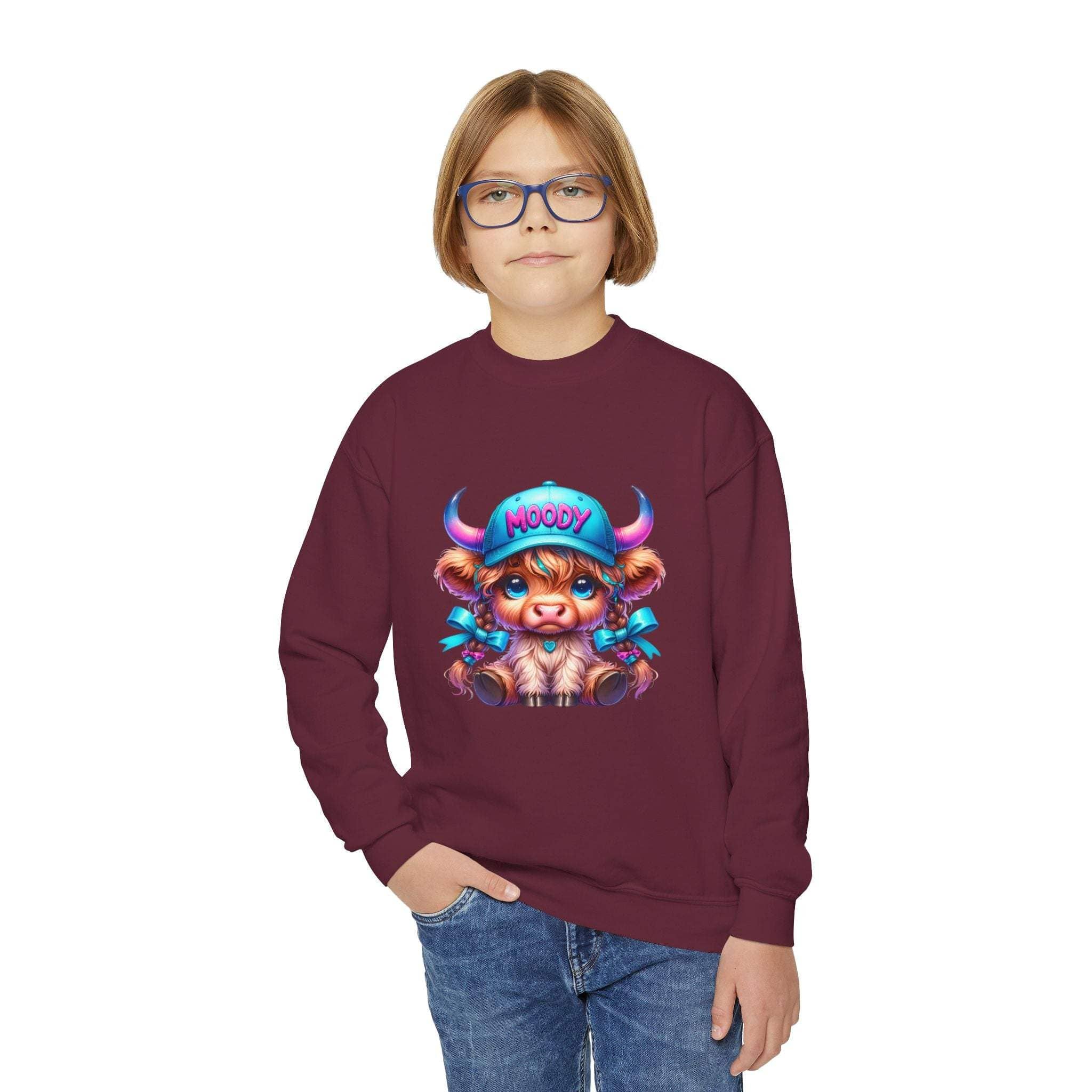 Child wearing maroon Moody Girl Highland Cow sweatshirt with colorful cartoon cow design and blue jeans