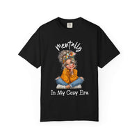 Black t-shirt with a graphic of a woman in an orange sweater and text 'mentally In My Cozy Era' on a white background
