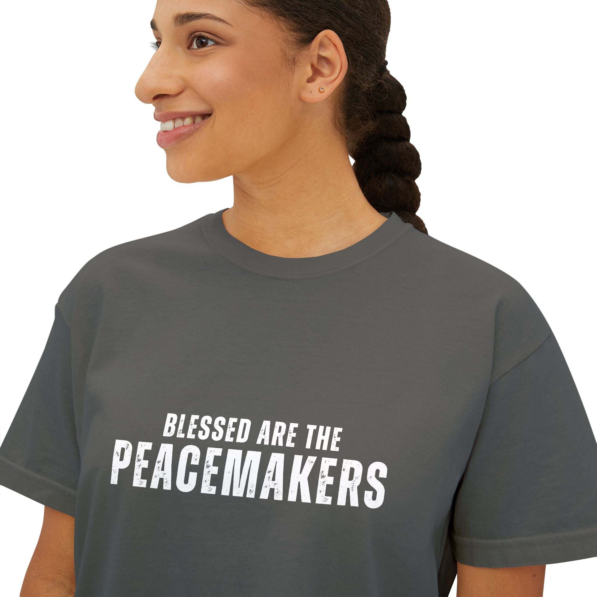 Woman wearing grey boxy tee with "Blessed are the Peacemakers" text, casual peace-themed shirt