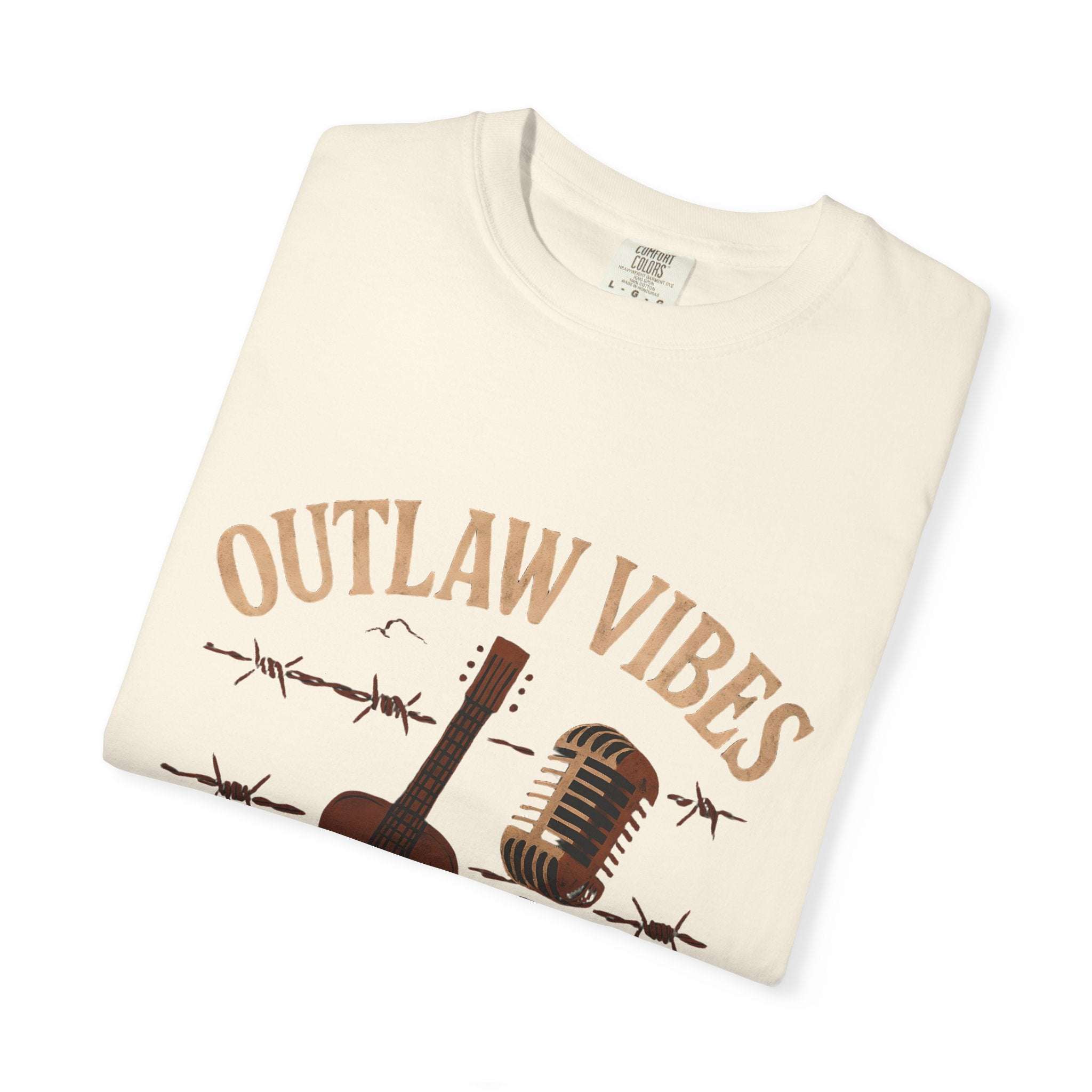 Folded cream-colored t-shirt with 'Outlaw Vibes' text and guitar graphic on a white background