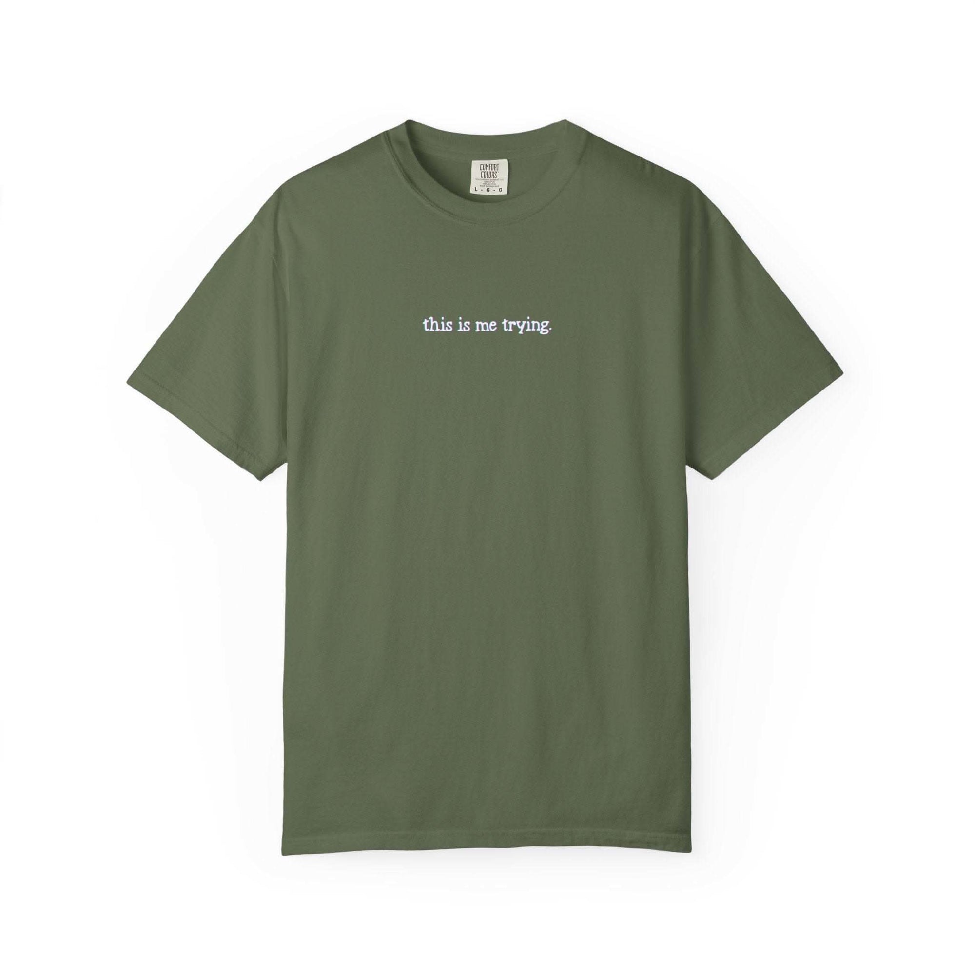 Green t-shirt with 'this is me trying' text on a white background