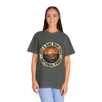 woman wearing olive green National Parks T-Shirt with sunset and mountain graphic