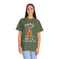 Woman wearing olive green Mentally in My Cozy Era t-shirt with graphic girl illustration and hand-lettered text.