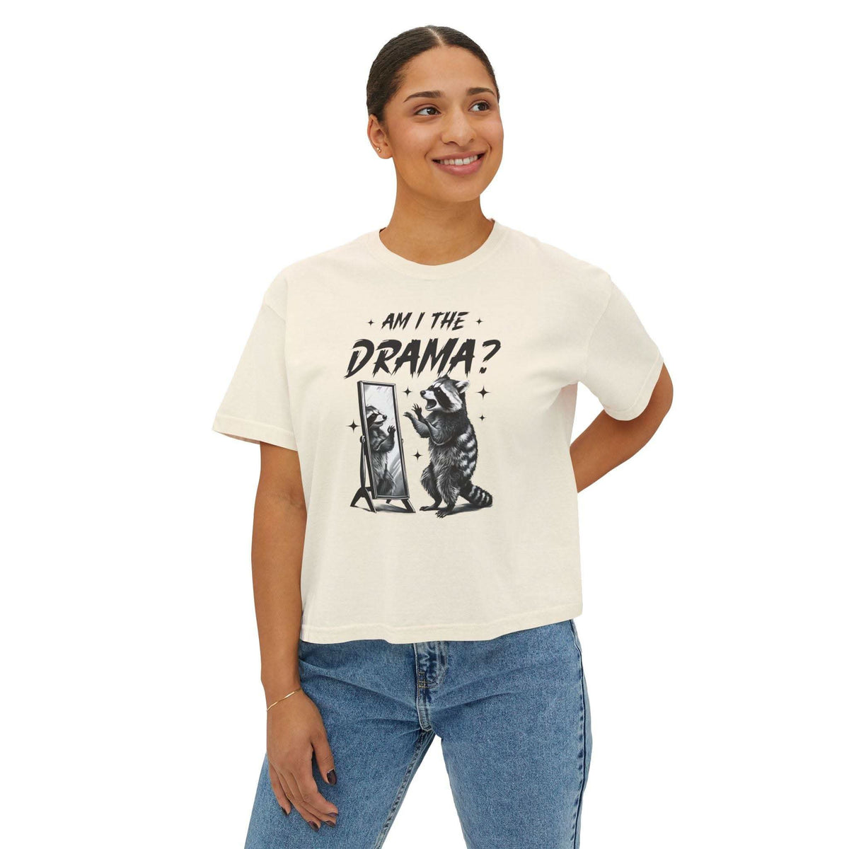 Woman wearing white boxy tee with "Am I The Drama?" raccoon graphic and casual jeans