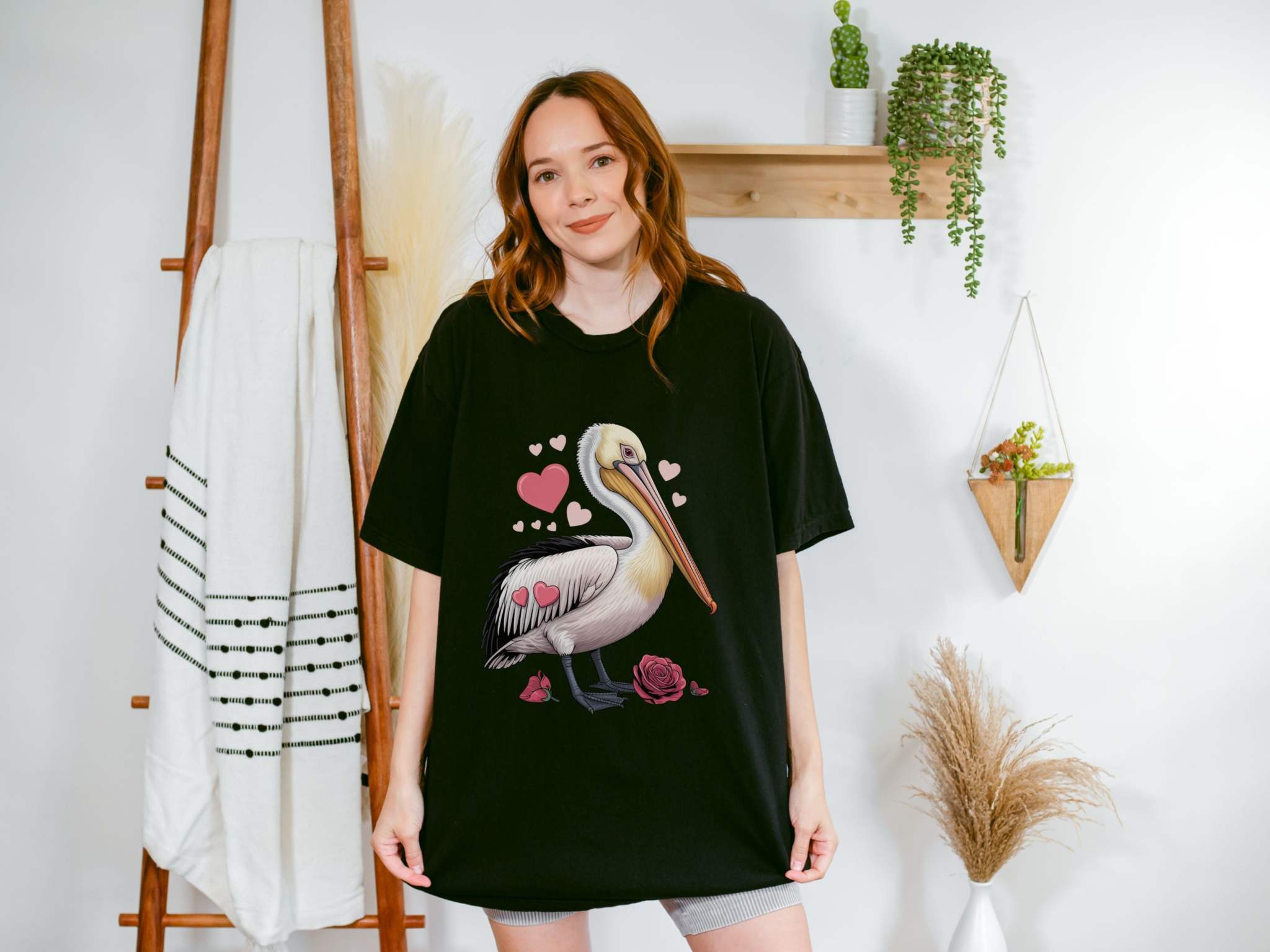 Woman wearing black Valentine's Pelican Hearts T-Shirt with pelican and heart design standing indoors