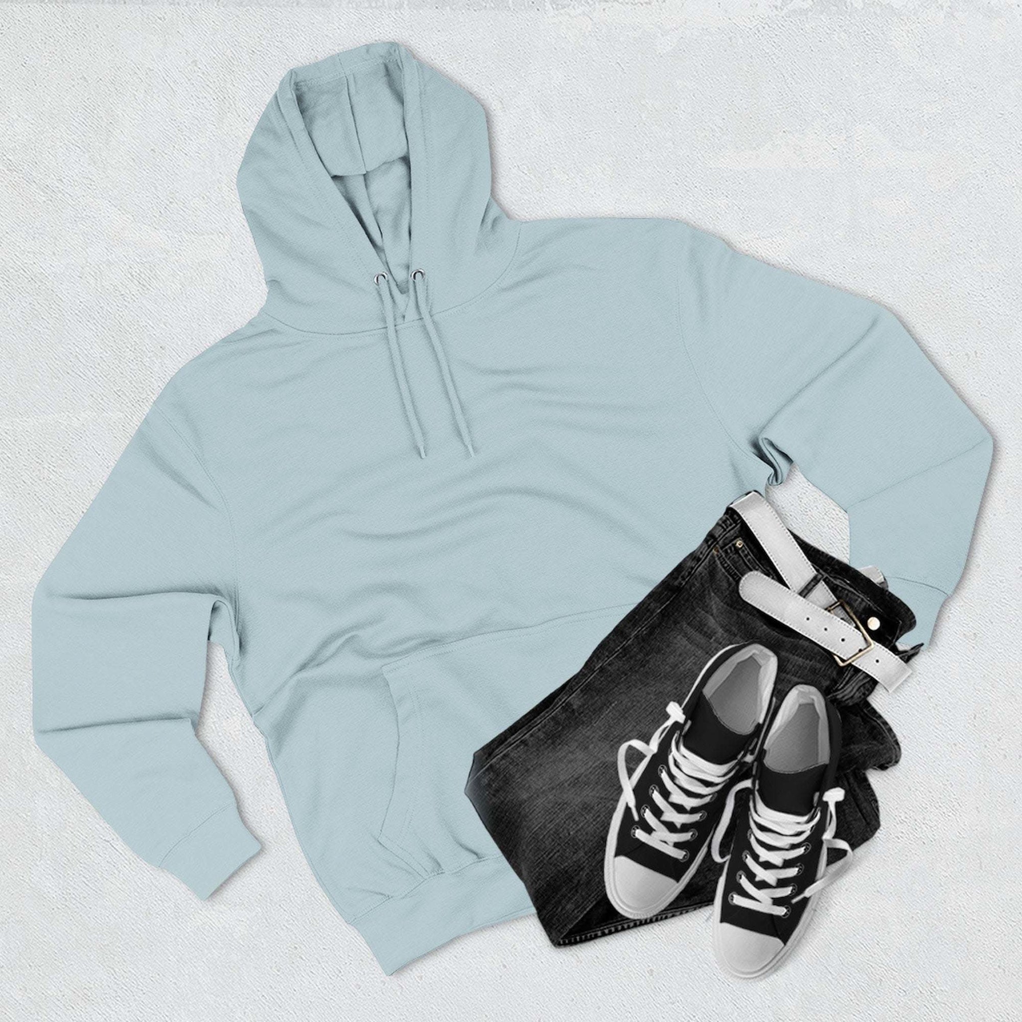 Light blue fleece hoodie with drawstrings, paired with black jeans and black and white sneakers on a white background
