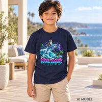 Boy wearing a navy Local Legend youth T-shirt with a neon cat riding a dolphin graphic and tan shorts on an ocean-view terrace.