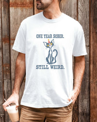 Male model wearing a white Comfort Colors 1717 t-shirt featuring a navy cat in a red party hat and “One Year Sober. Still Weird.” lettering.