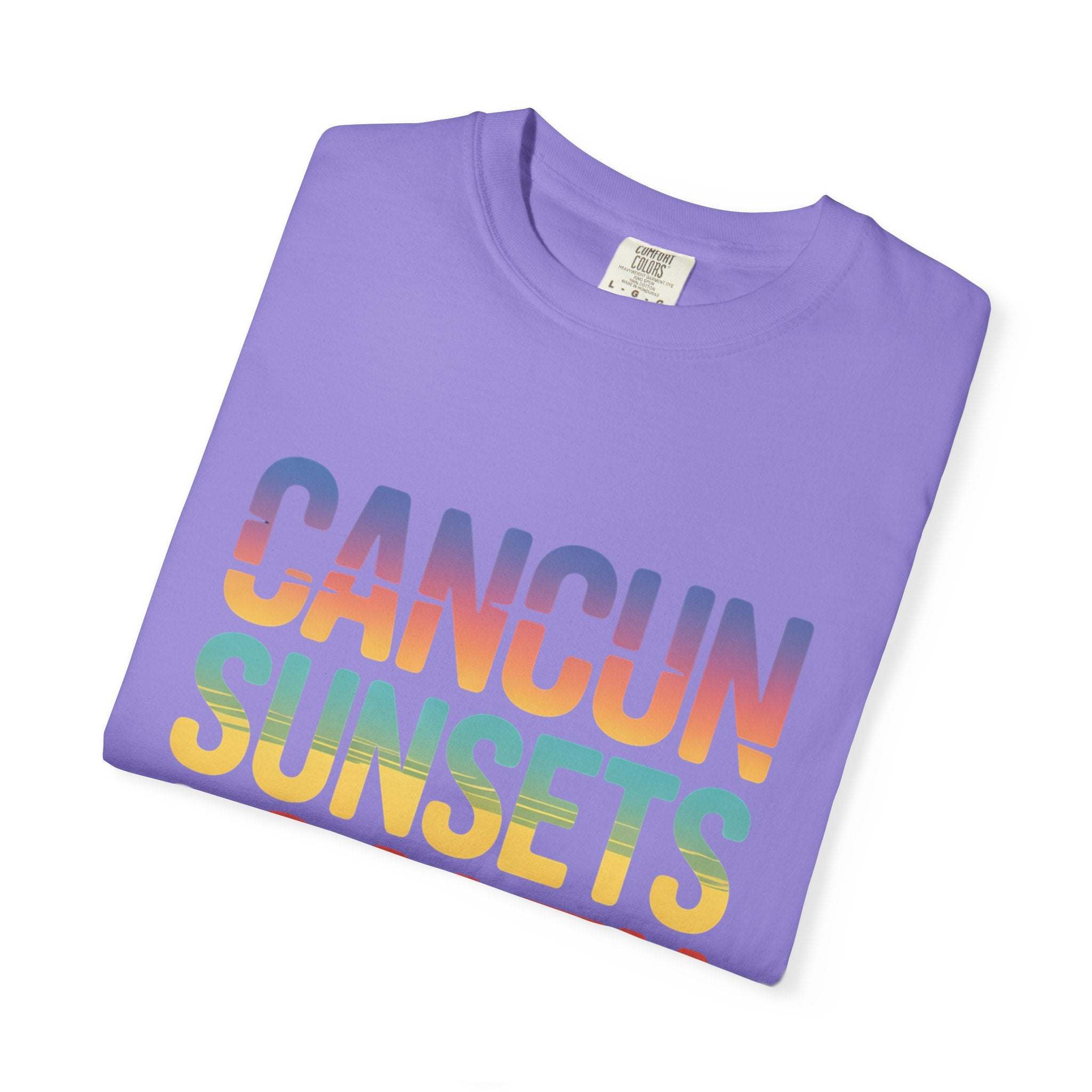 Folded purple t-shirt with 'Cancun Sunsets' text in rainbow colors on a white background