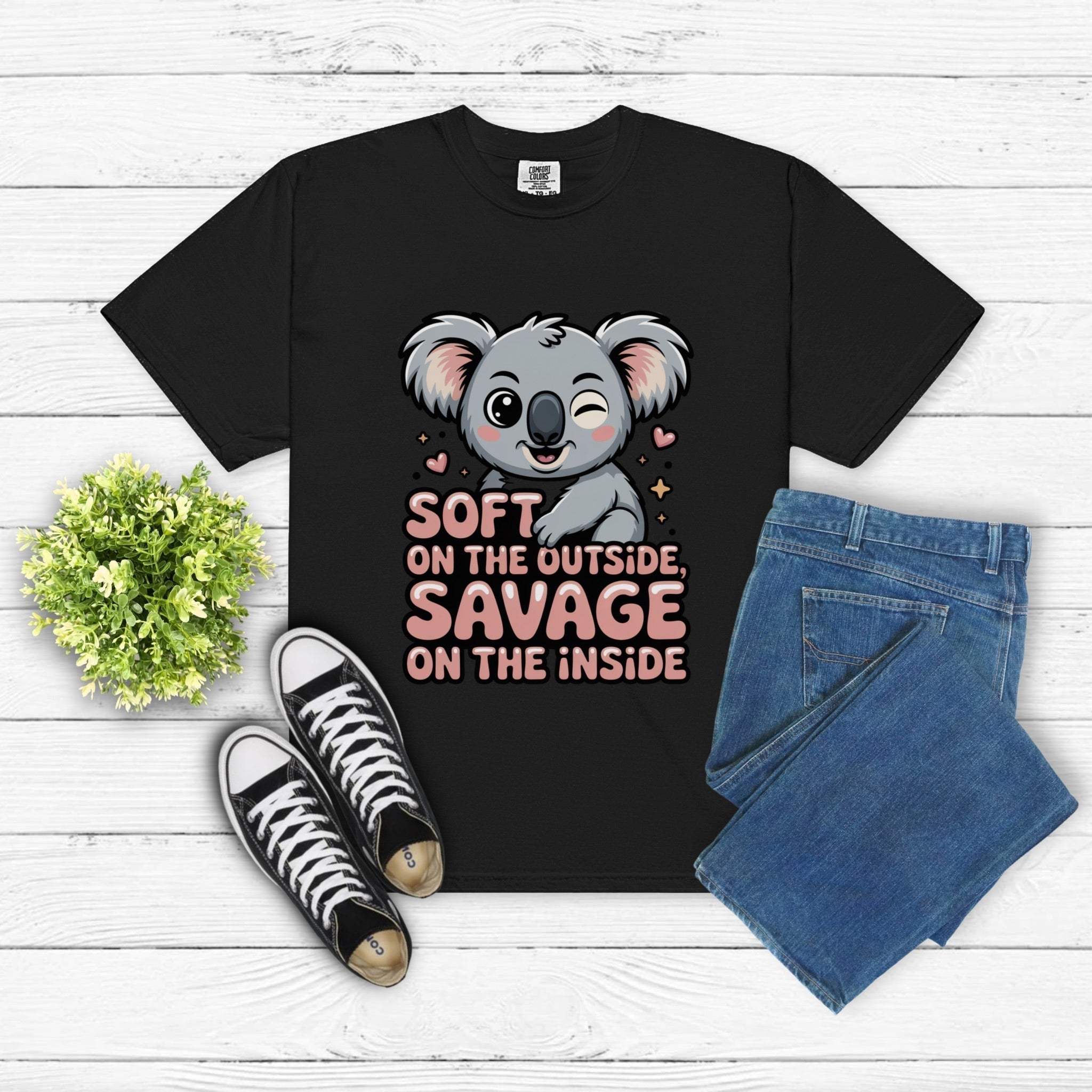 Black t-shirt with winking koala graphic and "Soft on the Outside Savage on the Inside" text, paired with jeans and sneakers on white wooden background