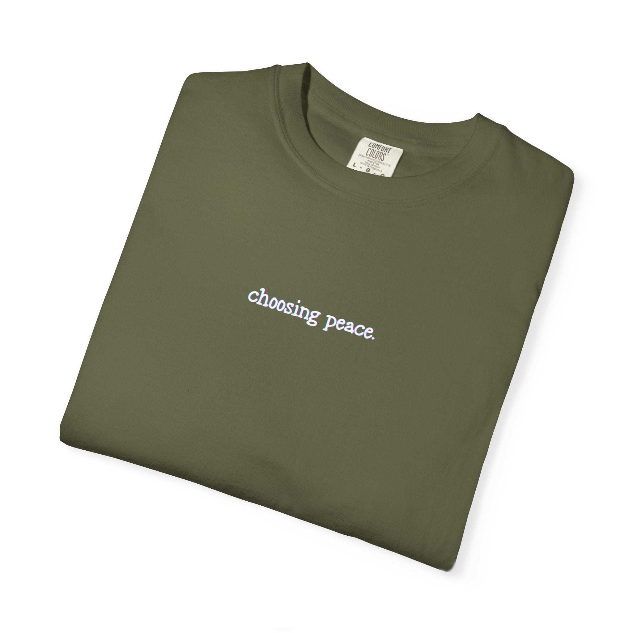 Folded green t-shirt with 'choosing peace' text on a white background