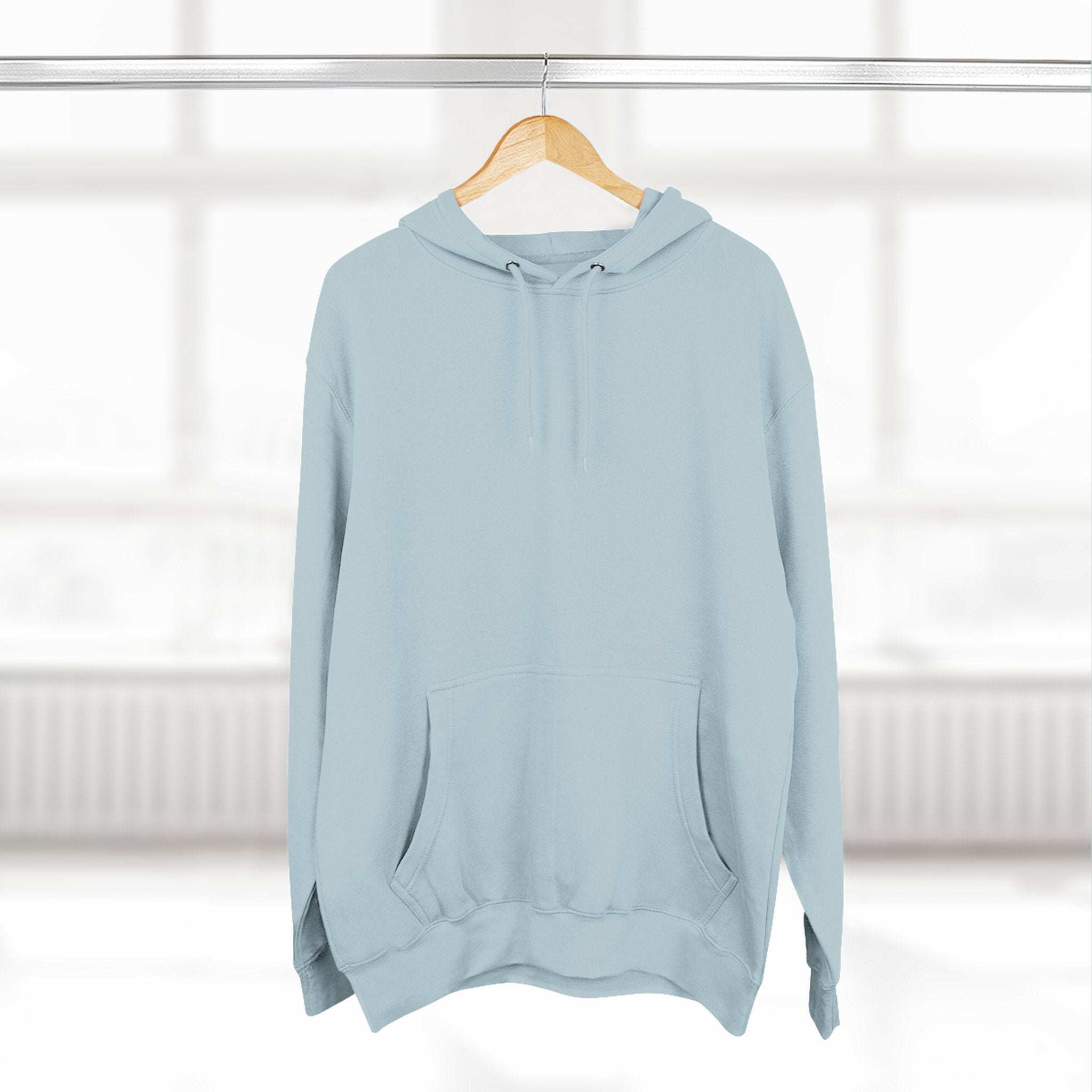 Light blue fleece hoodie with adjustable hood and kangaroo pocket hanging on wooden hanger in bright room