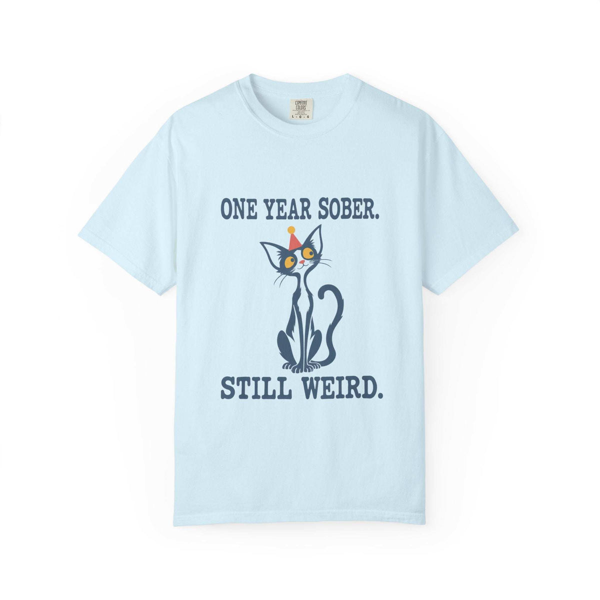 Flat lay of a chambray blue Comfort Colors 1717 t-shirt featuring a navy cat in a red party hat and “One Year Sober. Still Weird.” lettering.
