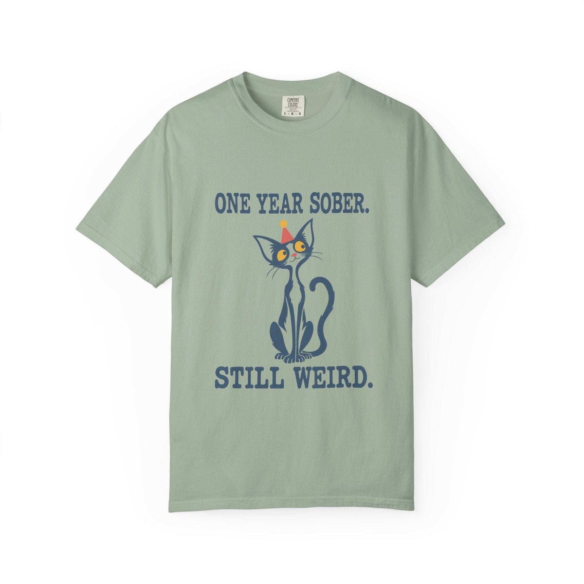 Flat lay of a bay green Comfort Colors 1717 t-shirt featuring a navy cat in a red party hat and “One Year Sober. Still Weird.” lettering.