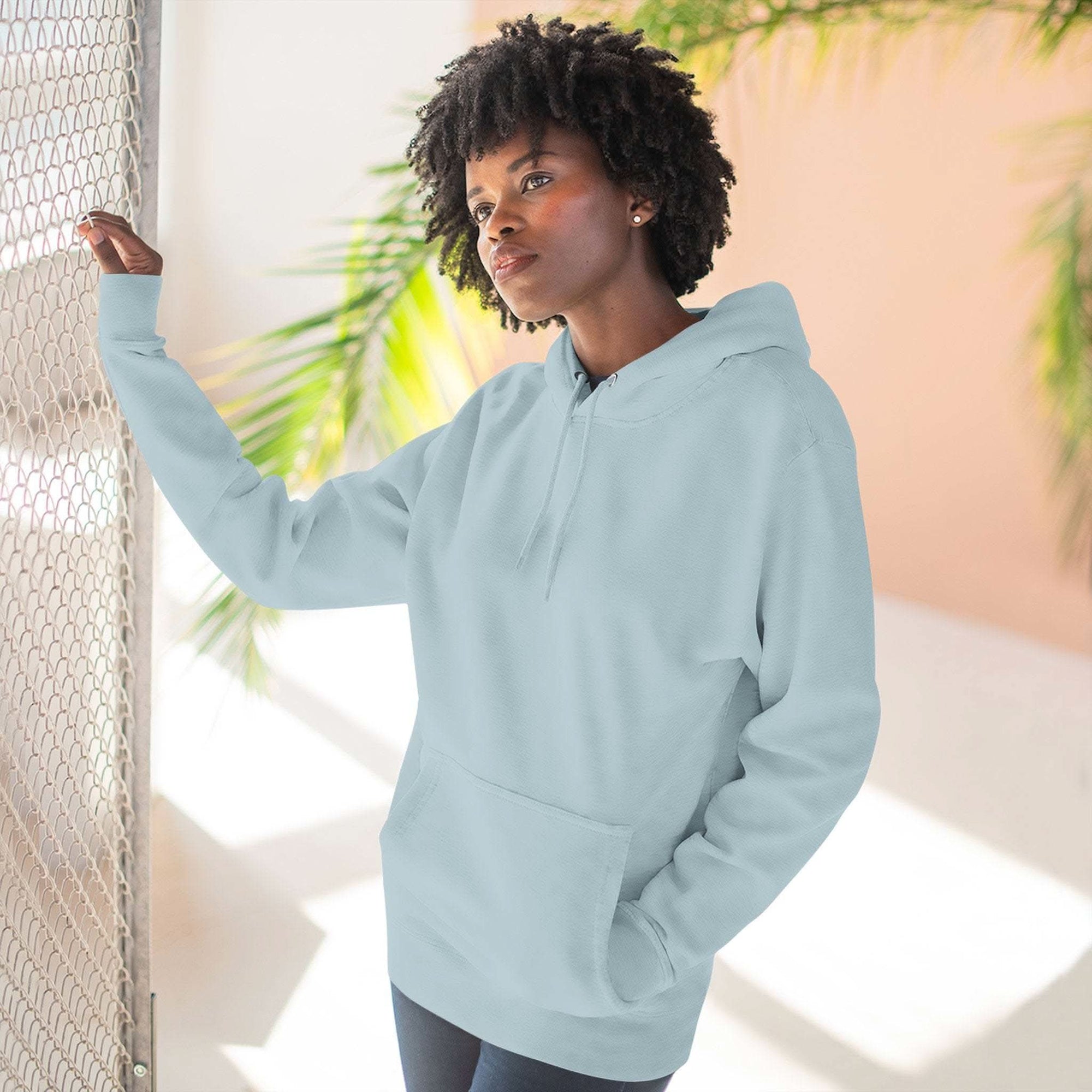 Woman wearing light blue soft fleece hoodie with adjustable hood and kangaroo pocket indoors