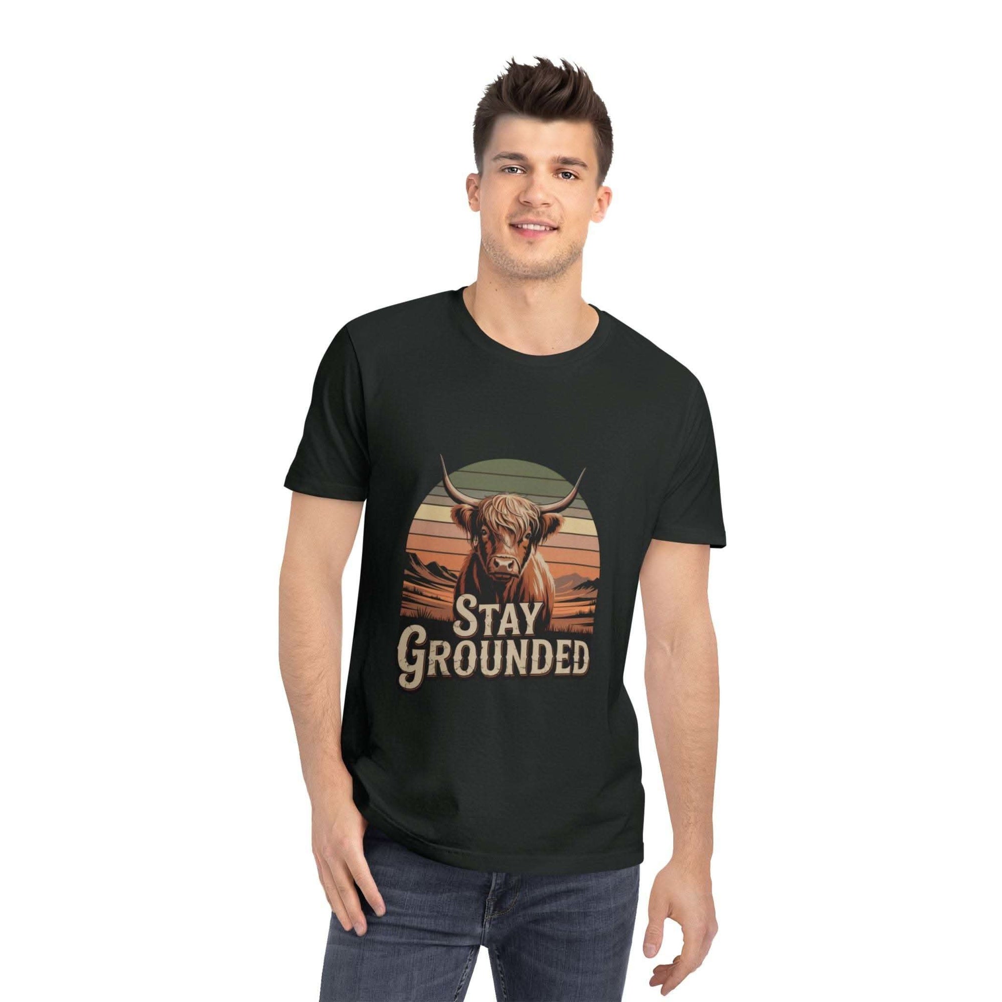 Person wearing a black t-shirt with a graphic of a cow and 'Stay Grounded' text on a white background