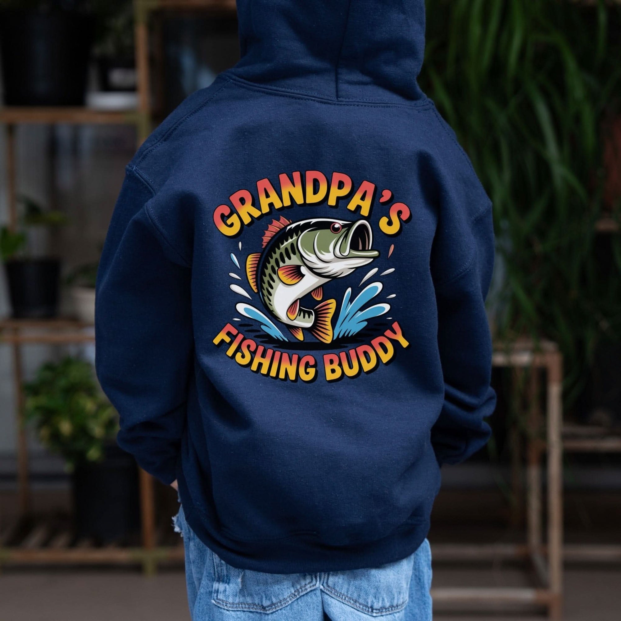 Youth wearing Grandpas Fishing Buddy Hoodie by the lake on a cool morning