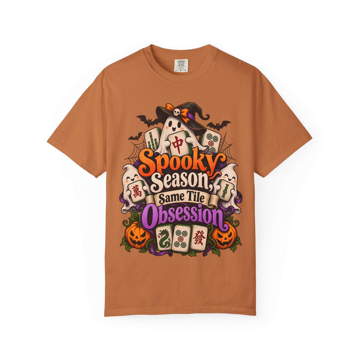 Flat lay of a yam orange Halloween mahjong T-shirt with ghosts, pumpkins, mahjong tiles and “Spooky Season, Same Tile Obsession” lettering.