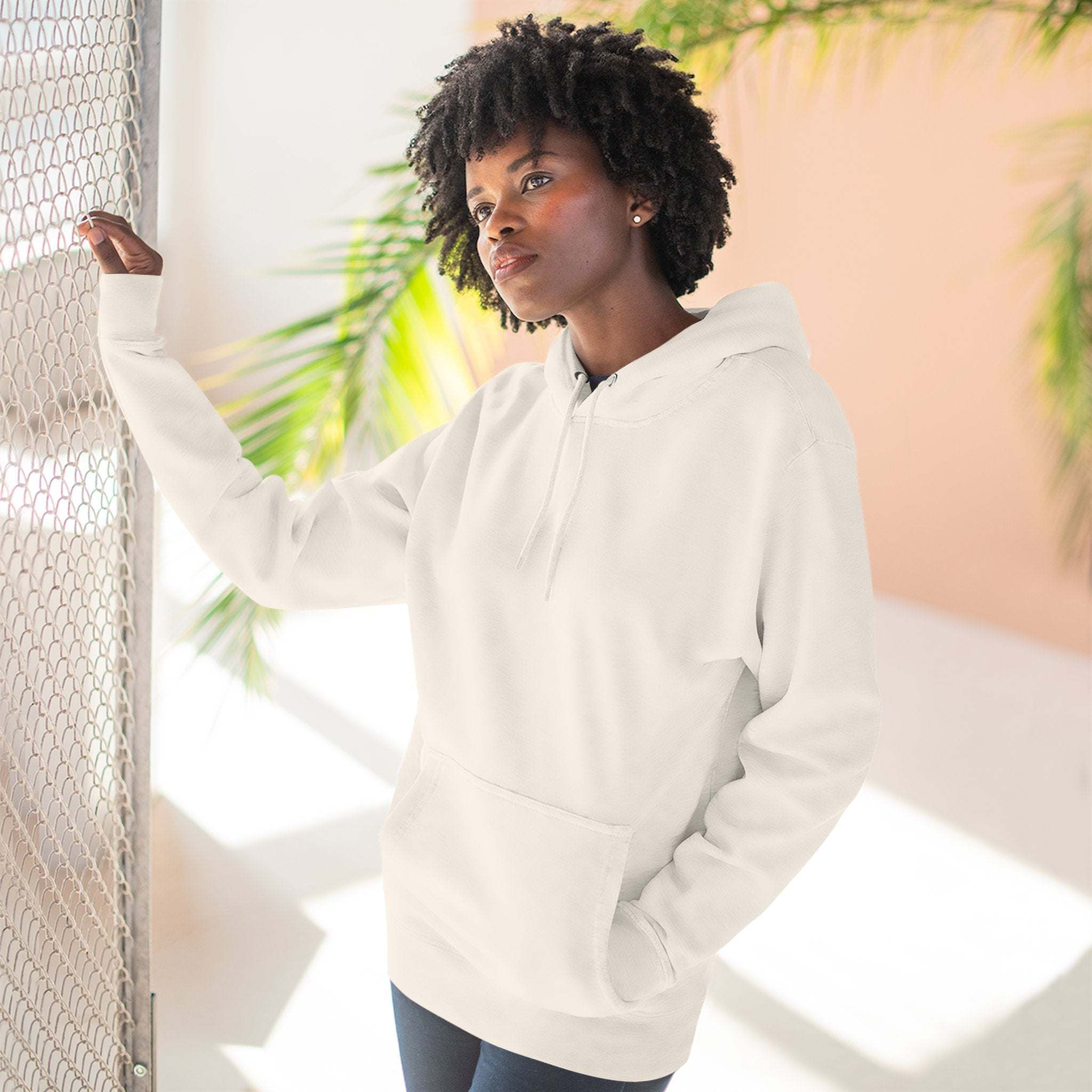Woman wearing white fleece hoodie with kangaroo pocket indoors near window