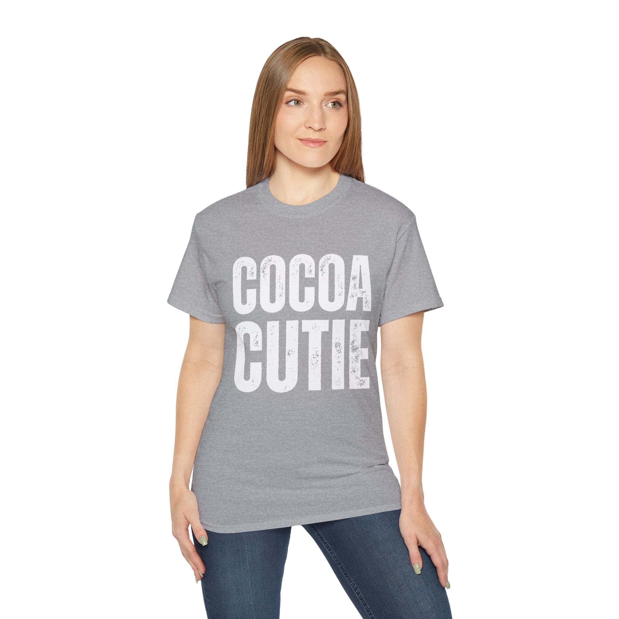 Woman wearing distressed Cocoa Cutie Tee in gray with bold white text, styled casually with jeans