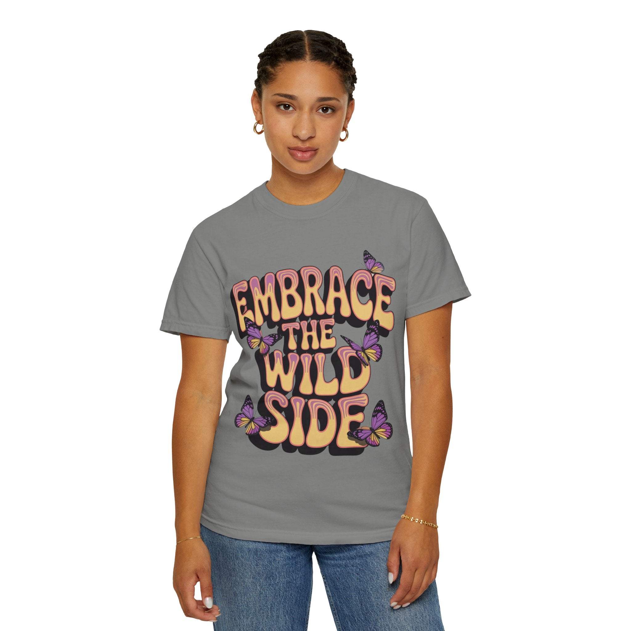 Garment-dyed T-shirt with "Embrace the Wild Side" print and butterflies on gray fabric worn by woman