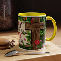 Mug with floral design and yellow handle on a wooden surface with coffee beans and a spoon.