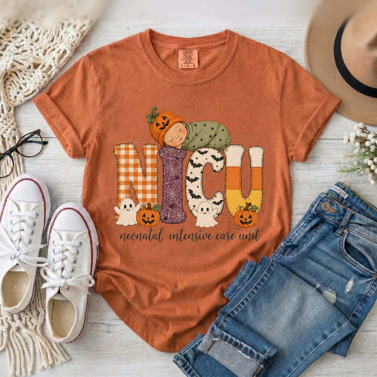 Yam orange NICU nurse Halloween T-shirt with patchwork lettering, a sleeping baby in a pumpkin hat, ghosts, and jack-o’-lanterns.