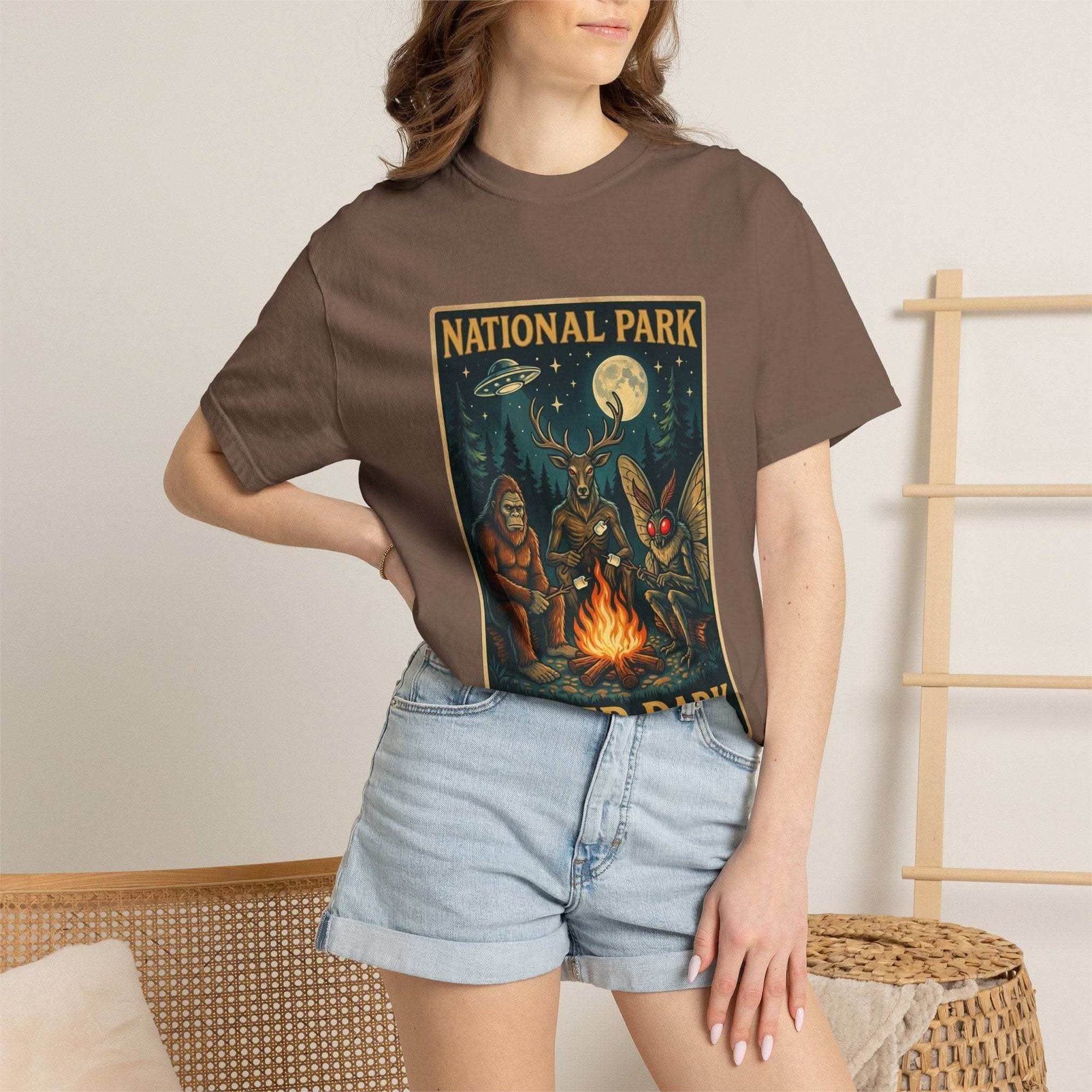 National Park After Dark t-shirt with campfire, moonlit trees, Sasquatch, and Mothman nocturnal creatures design